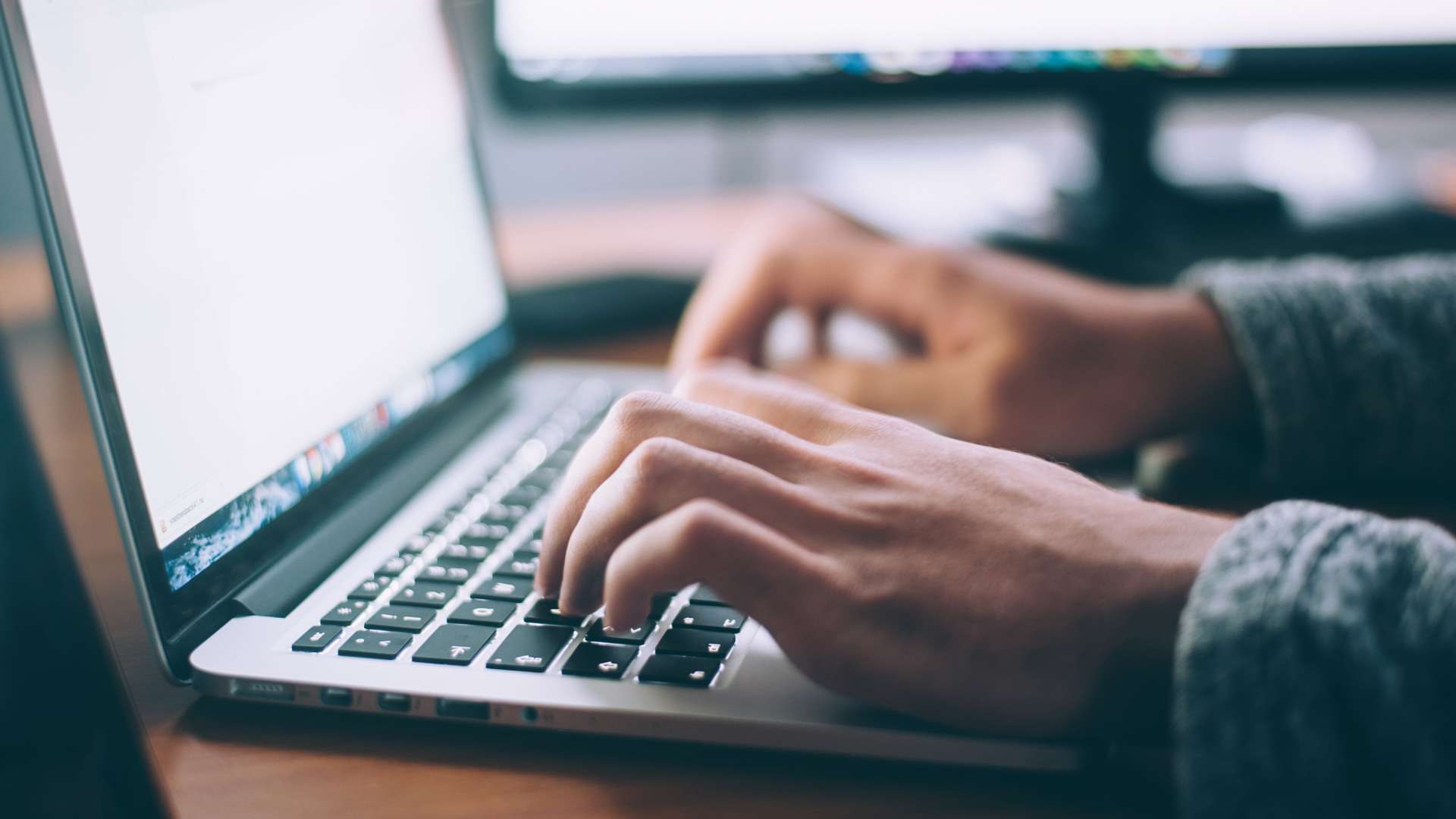Photo of a person typing on a laptop keyboard.