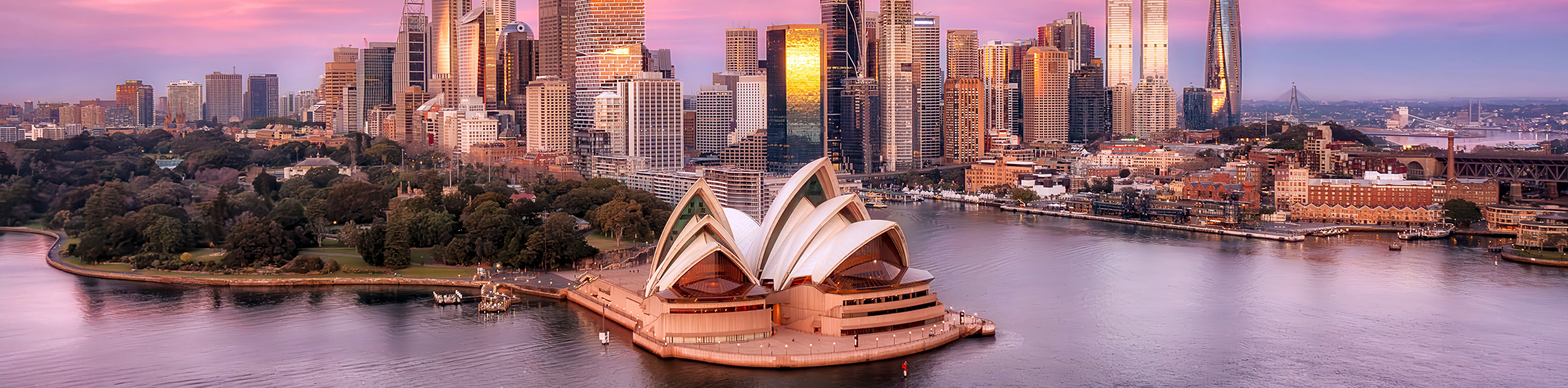 A beautiful pink and purple sunset over a omodern harbour city