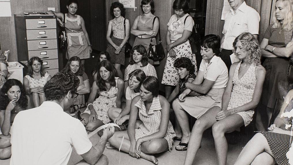 black & white image of young women in 1960s style clothing, sitting casually in a class room