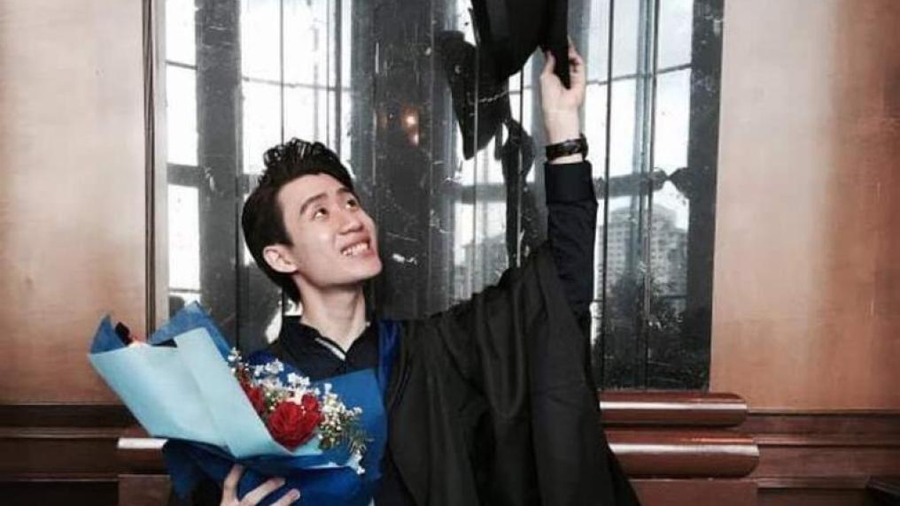 Malaysian graduate holding flowers and holding his cap up to the sky
