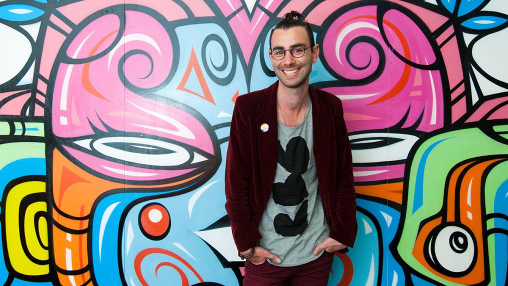Young man in on-trend clothing, in front of graffiti wall