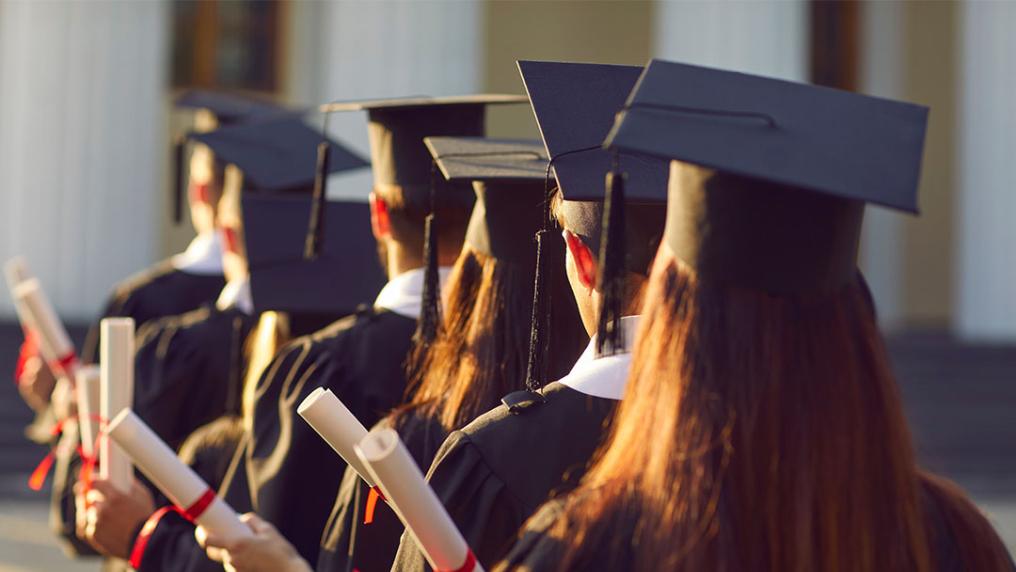 Students in graduation robes, holding scrolls.