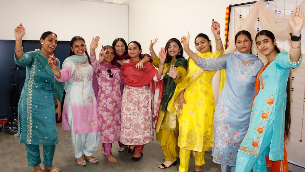 Row of smiling students in colourful Indian traditional dress.
